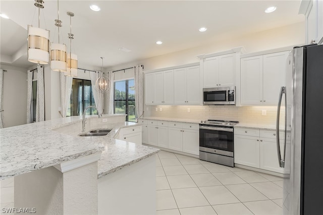 kitchen with hanging light fixtures, white cabinetry, appliances with stainless steel finishes, sink, and tasteful backsplash