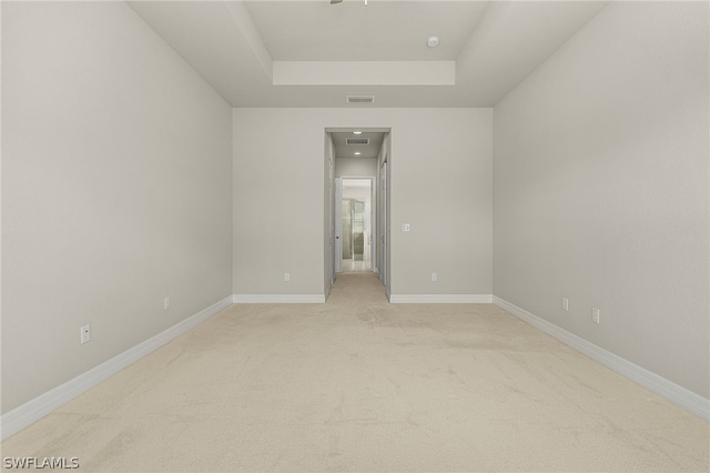 carpeted spare room featuring a raised ceiling