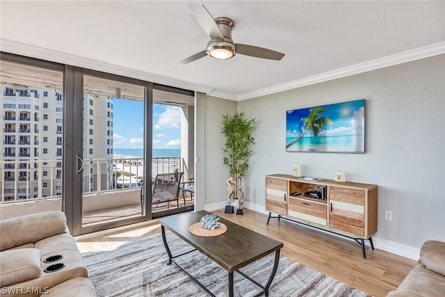 living room with ornamental molding, light hardwood / wood-style floors, ceiling fan, and a water view