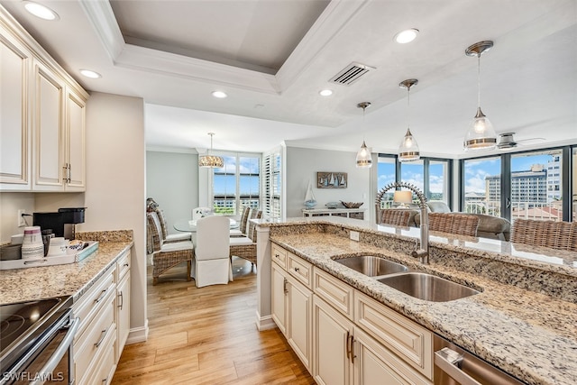 kitchen with decorative light fixtures, light hardwood / wood-style flooring, sink, and light stone counters