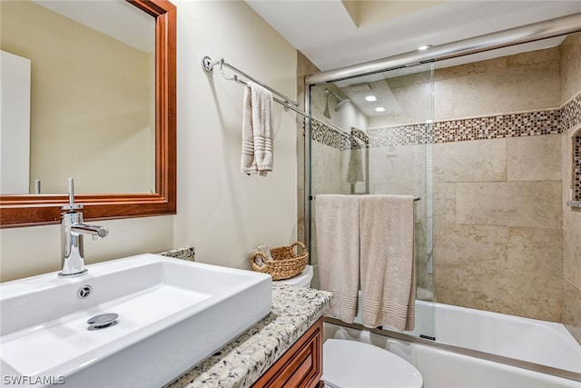 full bathroom with vanity, bath / shower combo with glass door, and toilet