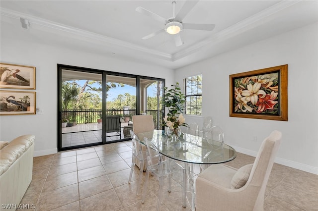 tiled dining area featuring ceiling fan, a tray ceiling, and crown molding