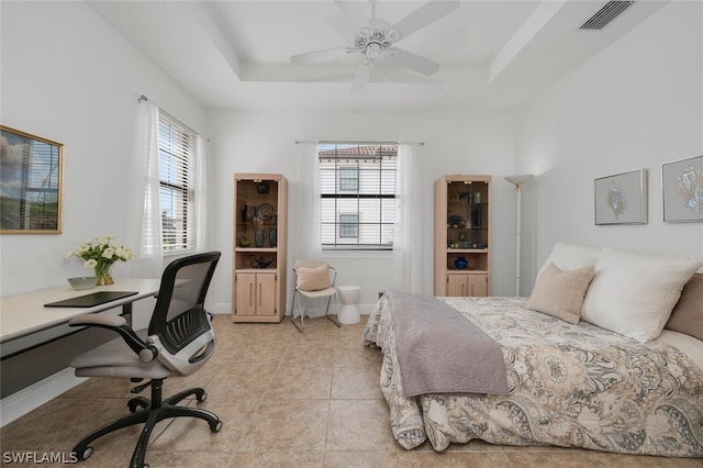 bedroom featuring ceiling fan, a tray ceiling, and light tile patterned flooring