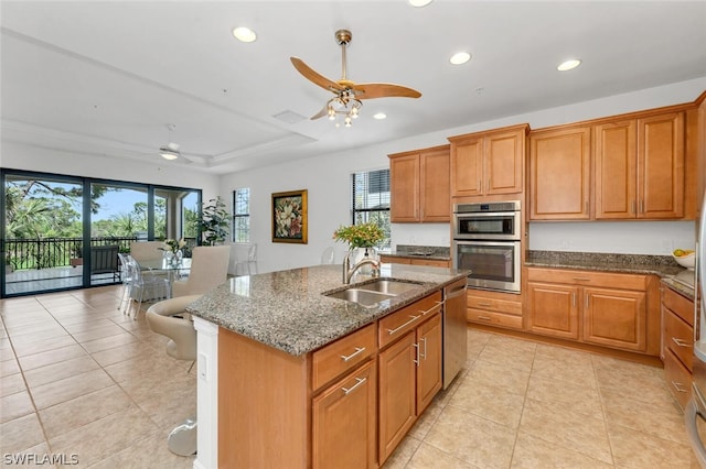 kitchen featuring a center island with sink, appliances with stainless steel finishes, a healthy amount of sunlight, dark stone counters, and sink