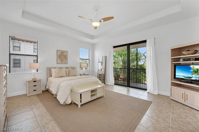 tiled bedroom with ceiling fan, access to outside, and a tray ceiling