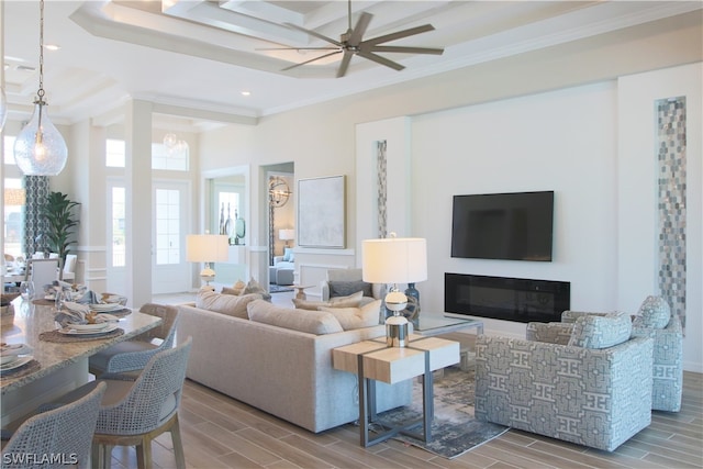 living room featuring hardwood / wood-style floors, a tray ceiling, ceiling fan, and ornamental molding