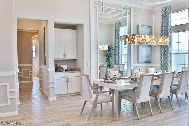 dining space with ornamental molding, a high ceiling, and light wood-type flooring