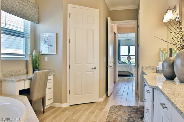 bathroom featuring plenty of natural light, ornamental molding, a bath, and vanity