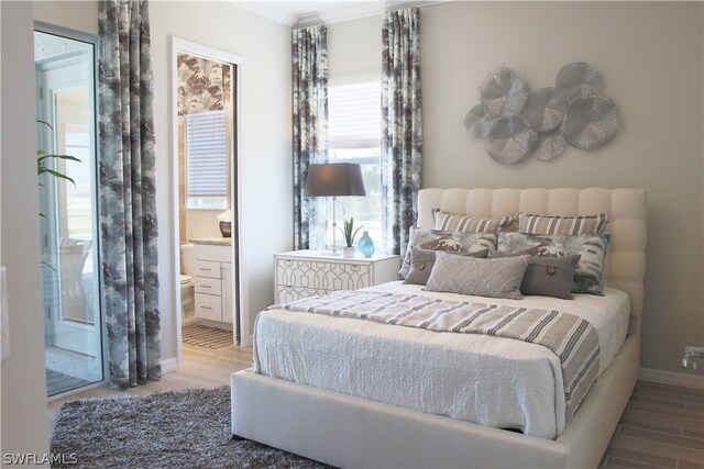 bedroom featuring ensuite bath, multiple windows, and light wood-type flooring