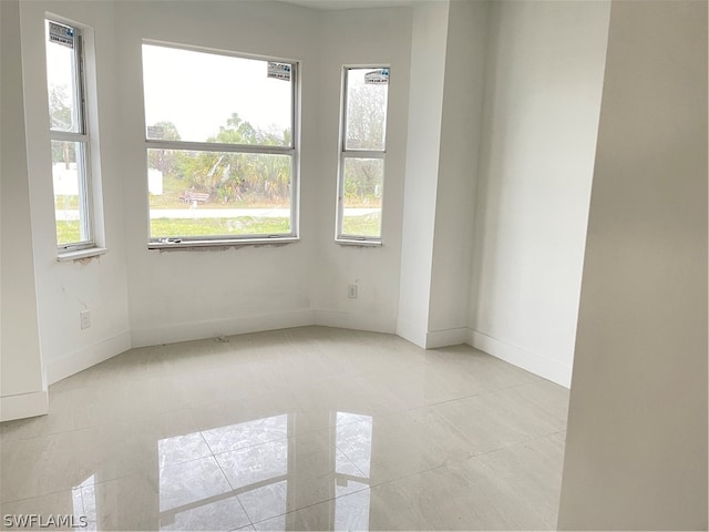 empty room featuring a healthy amount of sunlight and light tile patterned floors