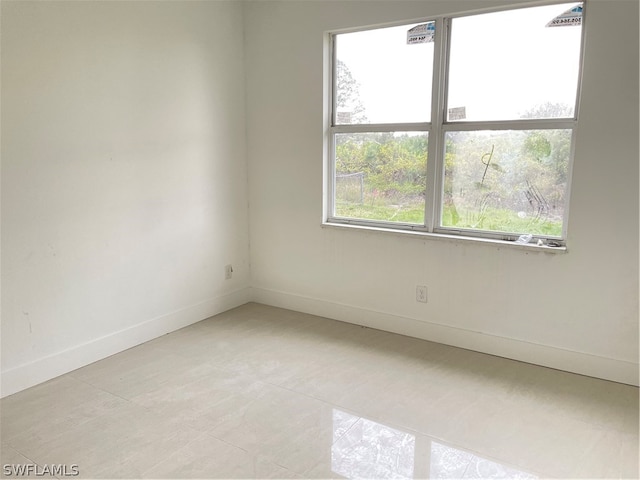 tiled spare room featuring a healthy amount of sunlight