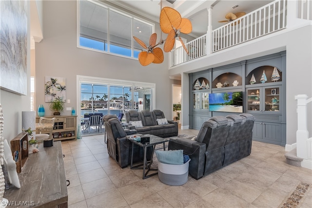 tiled living room featuring ceiling fan and a towering ceiling