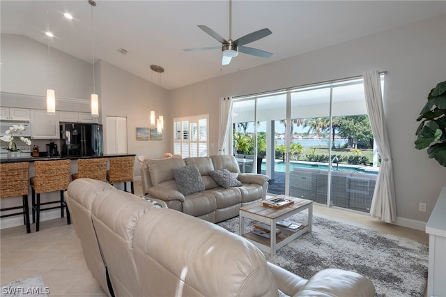 tiled living room with ceiling fan and high vaulted ceiling