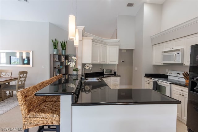 kitchen featuring white appliances, light tile patterned floors, kitchen peninsula, a kitchen bar, and sink