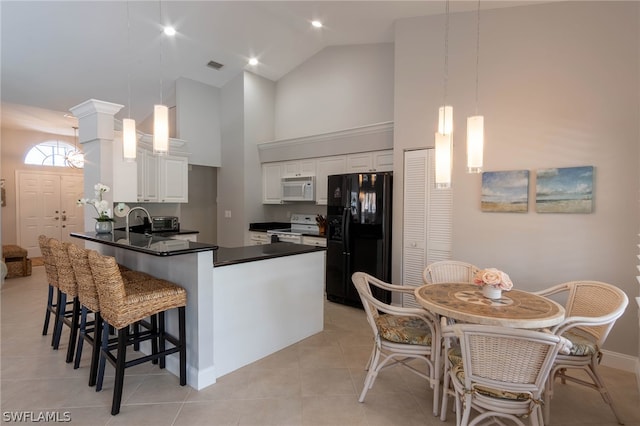 kitchen with light tile patterned flooring, white cabinets, high vaulted ceiling, white appliances, and kitchen peninsula