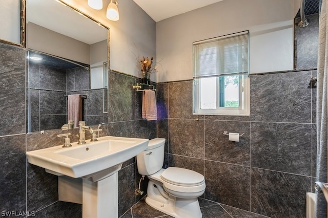 bathroom featuring tile patterned flooring, toilet, and tile walls