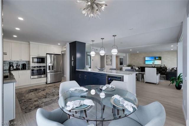 dining space with an inviting chandelier, light wood-type flooring, and wine cooler