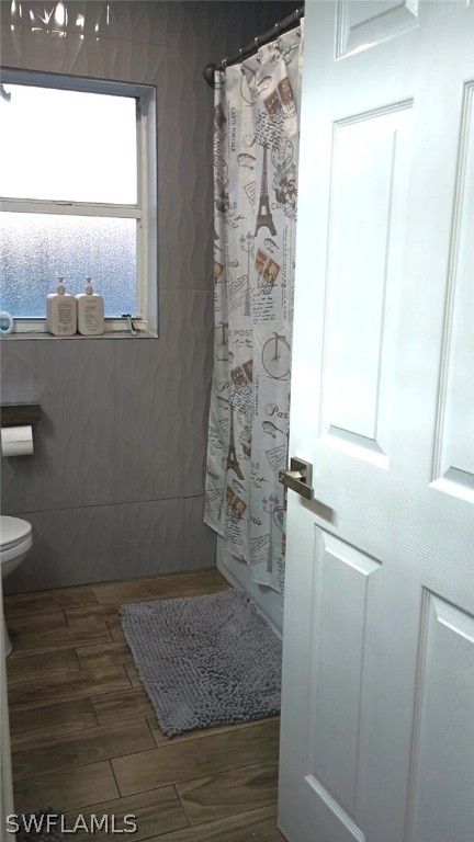 bathroom with toilet and tile walls