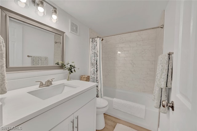 full bathroom with hardwood / wood-style flooring, vanity, shower / tub combo with curtain, and toilet