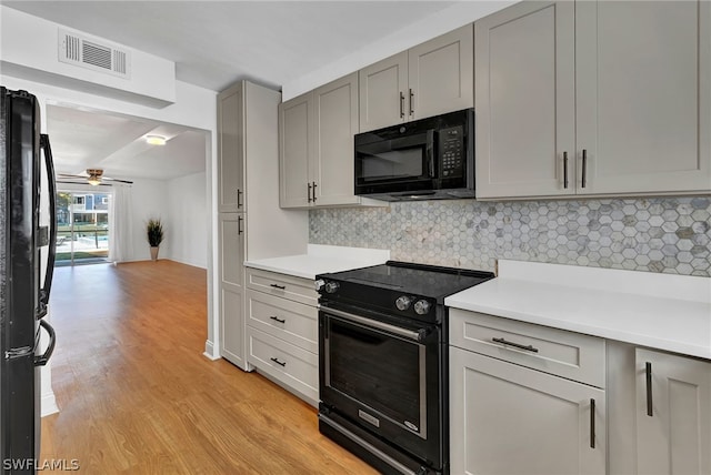 kitchen with backsplash, black appliances, light wood-type flooring, ceiling fan, and gray cabinets