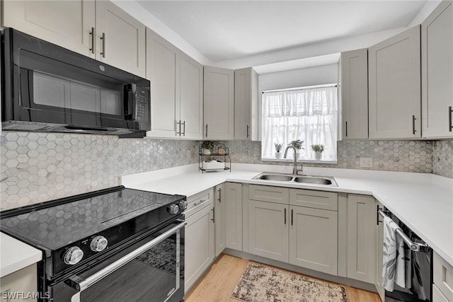 kitchen featuring sink, tasteful backsplash, light hardwood / wood-style floors, and electric range oven