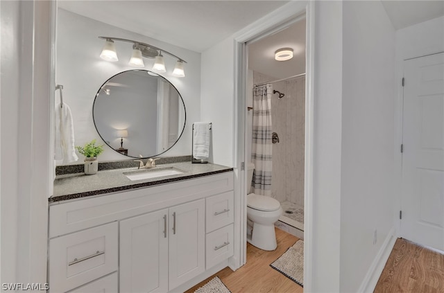 bathroom with hardwood / wood-style flooring, a shower with shower curtain, vanity, and toilet