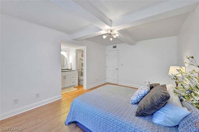 bedroom with beamed ceiling, ceiling fan, light wood-type flooring, and ensuite bath