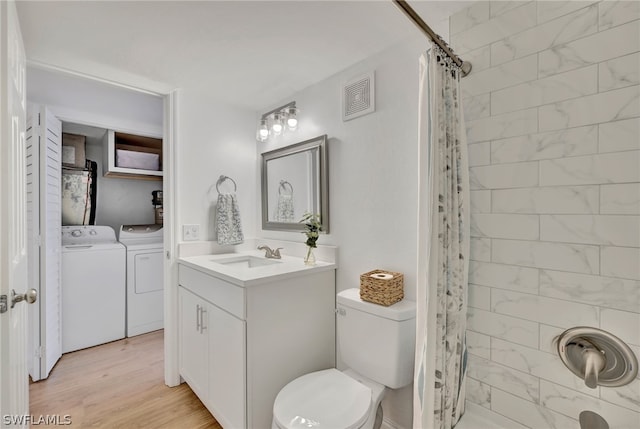 bathroom with toilet, separate washer and dryer, hardwood / wood-style flooring, and vanity