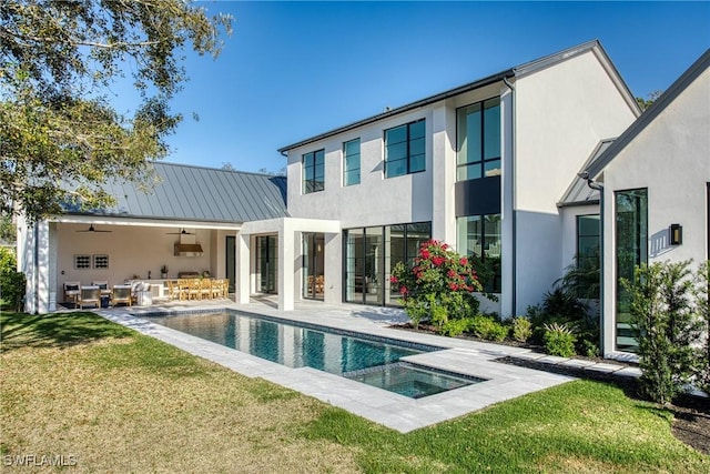 back of property featuring metal roof, a ceiling fan, a yard, an outdoor pool, and stucco siding