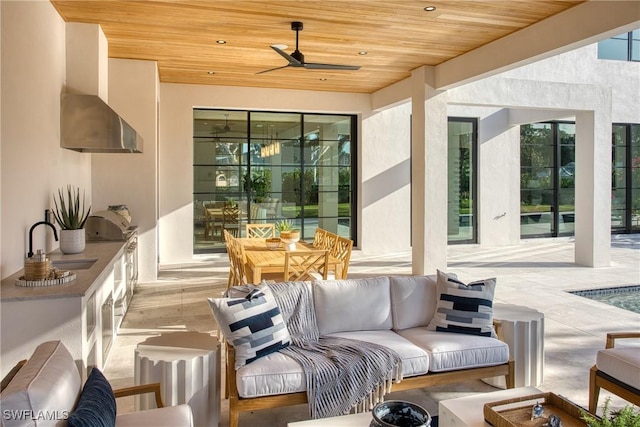 interior space with exterior kitchen, outdoor lounge area, a sink, and a ceiling fan