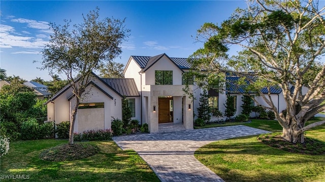 view of front of property featuring metal roof, an attached garage, a standing seam roof, decorative driveway, and a front yard