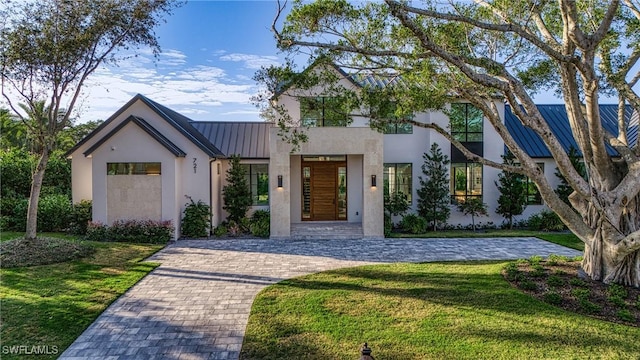 view of front facade featuring a standing seam roof, metal roof, a front lawn, and stucco siding