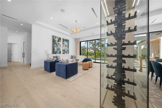 living room featuring a tray ceiling, recessed lighting, wood finished floors, a chandelier, and baseboards