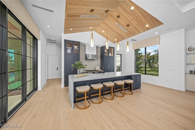 kitchen featuring visible vents, wooden ceiling, a large island, light wood-style flooring, and decorative light fixtures