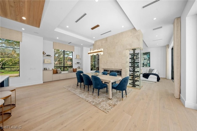 dining space with light wood-type flooring, visible vents, and a fireplace