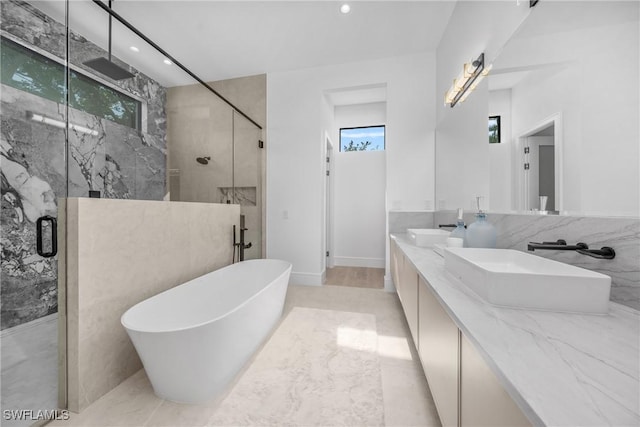 bathroom featuring a marble finish shower, double vanity, recessed lighting, a sink, and a freestanding tub