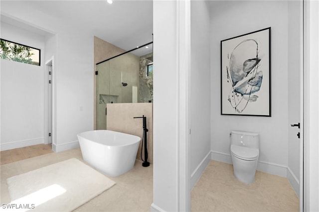 bathroom featuring toilet, a soaking tub, a shower stall, and baseboards