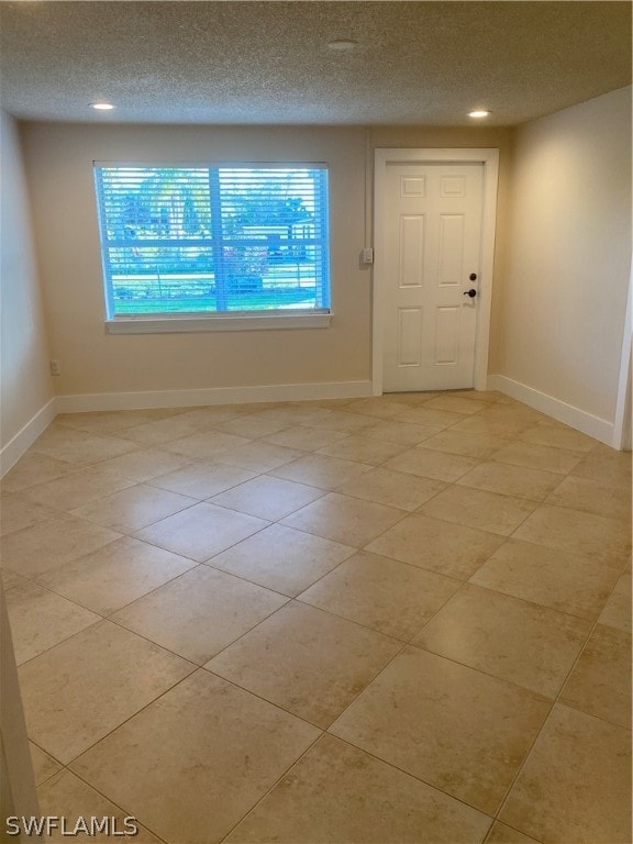 tiled empty room with a textured ceiling