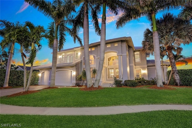 mediterranean / spanish-style home with a lawn and a garage