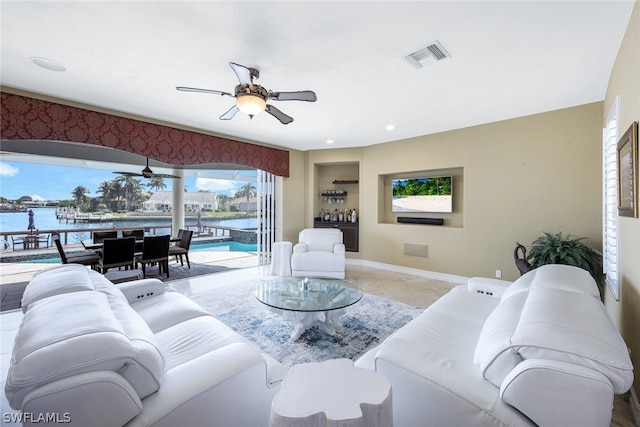 living room with a water view, light tile floors, and ceiling fan