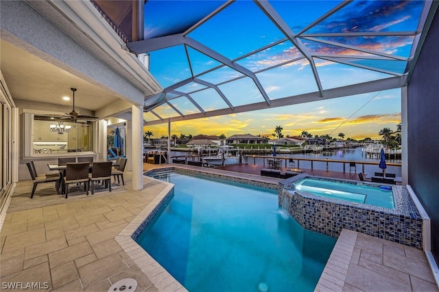 pool at dusk featuring an in ground hot tub, a lanai, ceiling fan, and a patio