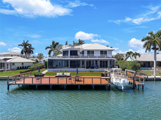 back of property with a lawn, a sunroom, and a water view