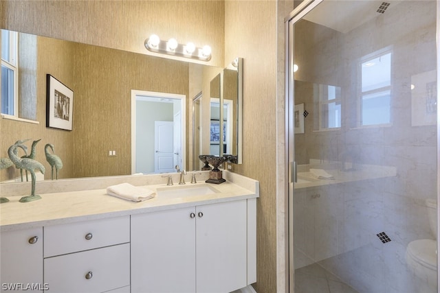 bathroom featuring a shower with door, toilet, and vanity