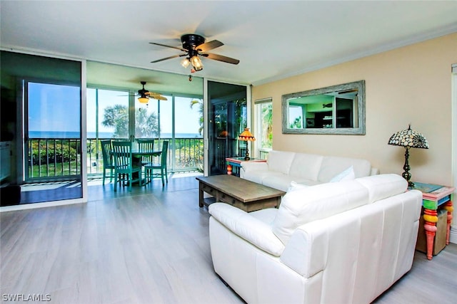 living room featuring ceiling fan, a wall of windows, hardwood / wood-style flooring, and a water view