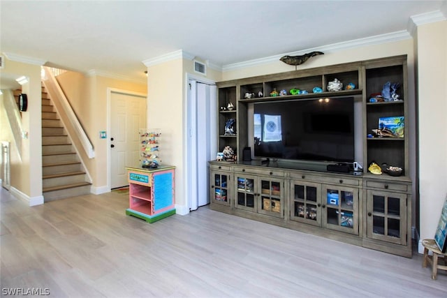 living area with ornamental molding, stairway, and wood finished floors