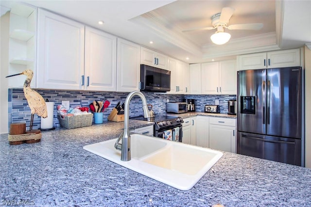 kitchen with appliances with stainless steel finishes, white cabinetry, tasteful backsplash, and a tray ceiling