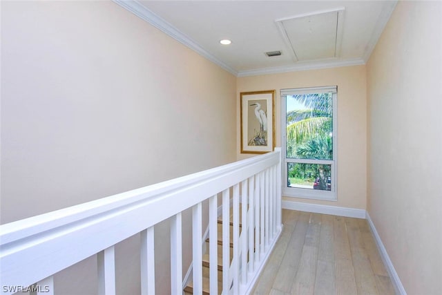 corridor with visible vents, baseboards, ornamental molding, light wood-type flooring, and attic access