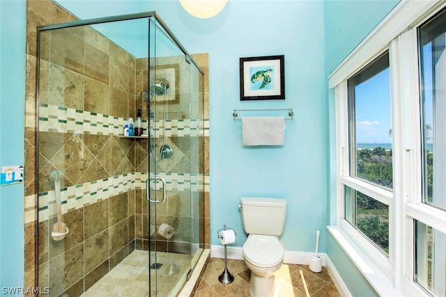 full bathroom with tile patterned flooring, toilet, a shower stall, and baseboards