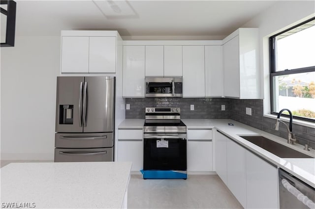 kitchen featuring appliances with stainless steel finishes, white cabinetry, sink, and tasteful backsplash