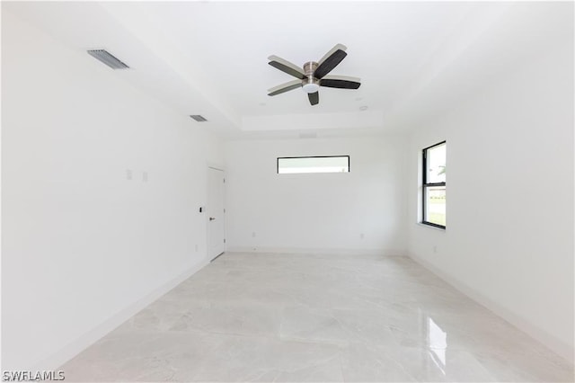 unfurnished room with tile floors, ceiling fan, and a raised ceiling